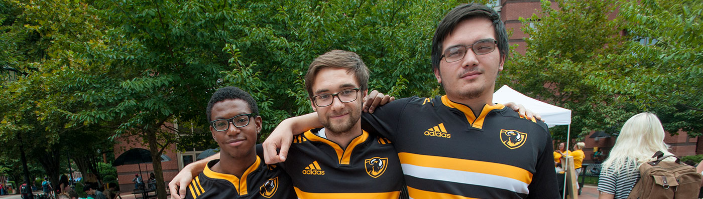 Three students wearing black and gold polo shirts